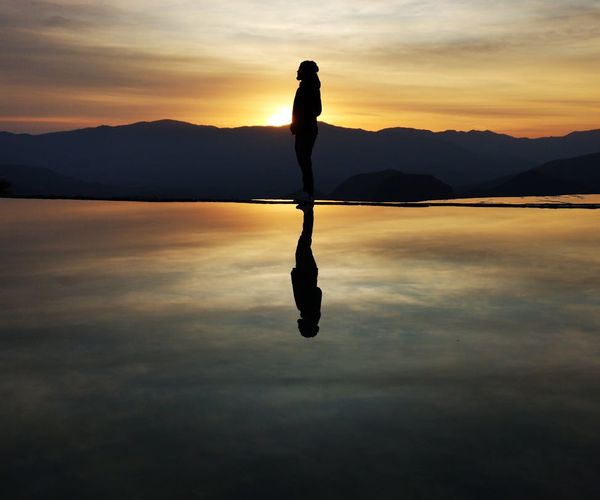 Silhouette of a person meditating during a beautiful sunrise over mountains.